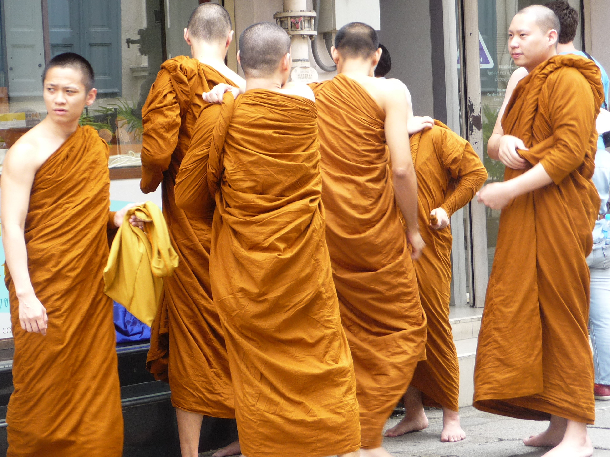 Young monka change their robes on the street outside temple